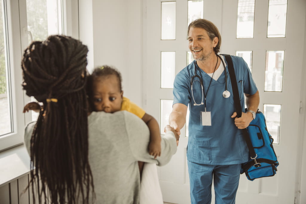 Doctor greeting a mother and child in the consulting room